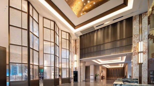 A spacious lobby with large windows, a modern ceiling design, and marble countertops. - REZEN HOTEL (Wuxi)