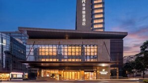 A modern hotel building with a prominent vertical sign, large glass windows, and a flat roof. - REZEN HOTEL (Wuxi)