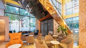 A modern lobby with a staircase, seating area, and large windows. - REZEN HOTEL (Wuxi)