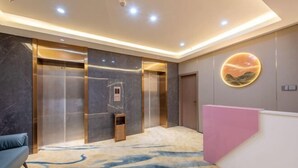 Eine moderne Hotelhalle mit Marmorwänden, einer Rezeption und einem Aufzug.