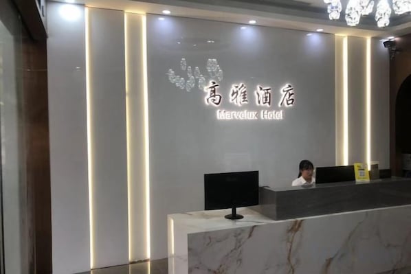 A hotel reception desk with a marble counter and a digital screen. - Gaoya Holiday Hotel (Guangzhou Panyu Chimelong Dashi Metro Station Branch) (Guangzhou)