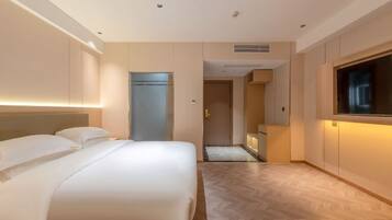 Una habitación de hotel con cama, televisión y puerta que da a un baño.