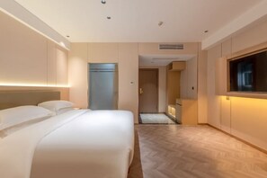 A hotel room with a bed, a TV, and a door leading to a bathroom.