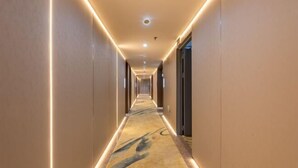 Ein Hotelgang mit Teppichboden und eingelassener Beleuchtung.