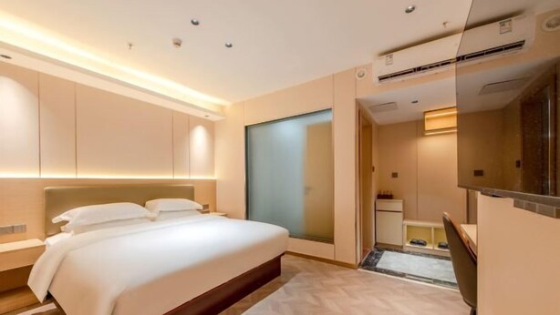 Ein modernes Hotelzimmer mit einem großen Bett, einer integrierten Garderobe und einem kleinen Badezimmer.