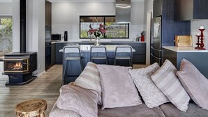 Una cocina moderna con una isla central, estufa integrada y un amplio ventanal con vistas a un jardín.