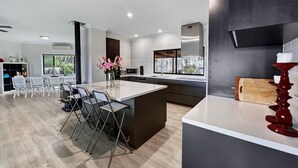 Una cocina moderna con una isla grande, muebles oscuros y vistas al exterior.