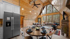 A modern kitchen with a stainless steel refrigerator, wooden ceiling, and large windows. - Creekfront Views! Hot Tub/ 2 King Bed En Suites/Secluded/Arcade/Firepit/FastWifi (Pigeon Forge)