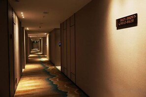 A hotel hallway with a carpeted floor, a sign with phone numbers, and a door at the end. - Yongfu County Golden Coast Royal Blessing Hotel (Yongfu)