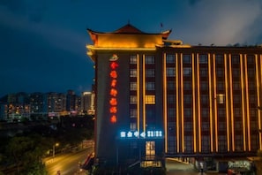 A hotel with a traditional architectural style, featuring a prominent entrance with illuminated signage.