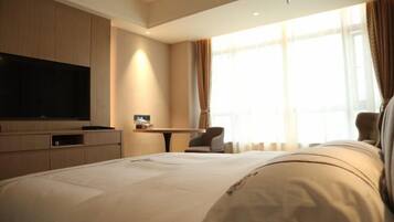 A hotel room with a large bed, a flat-screen TV, a desk, and a chair.