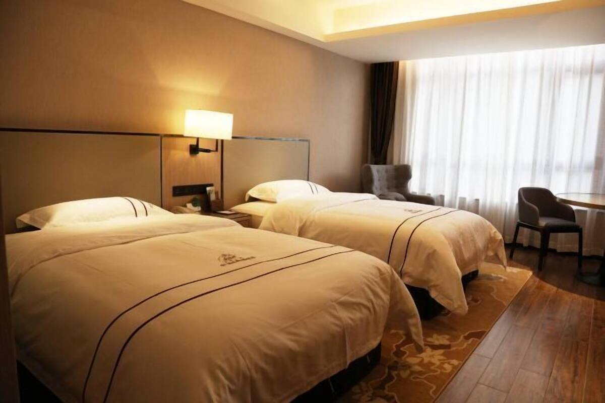 A hotel room with two beds, a desk, and a chair.