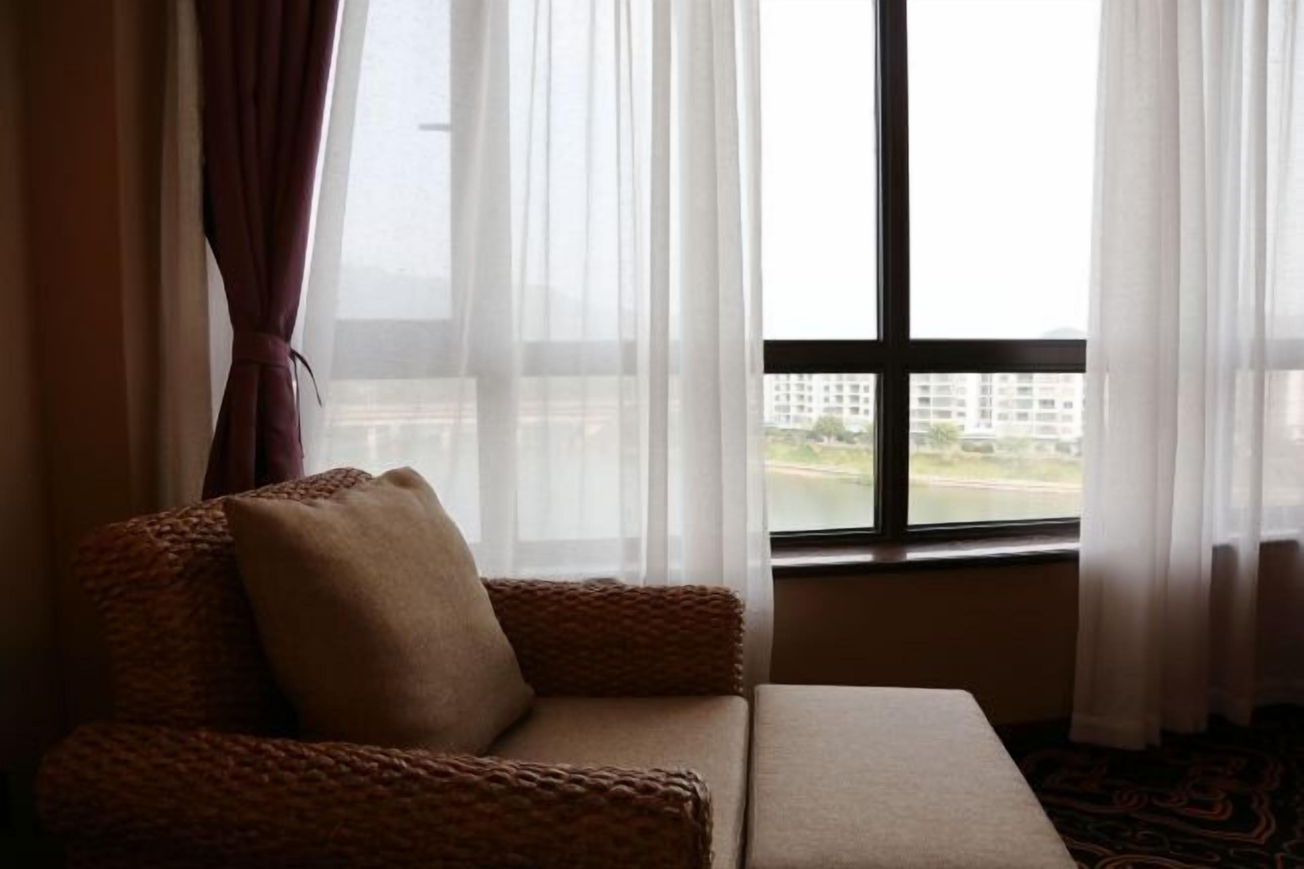 A room with a sofa and a window with curtains.