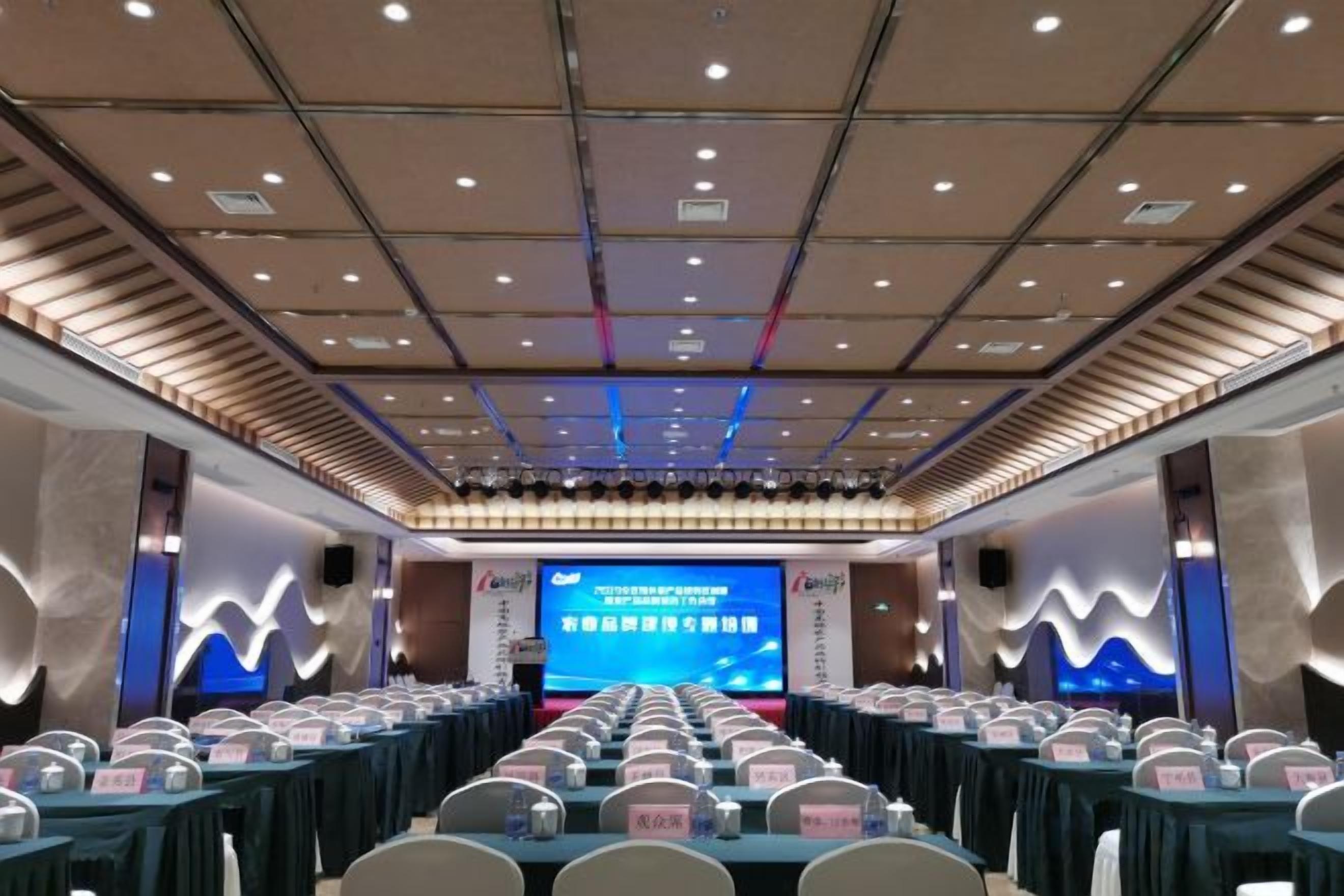 A conference room with a stage, rows of tables, and chairs.