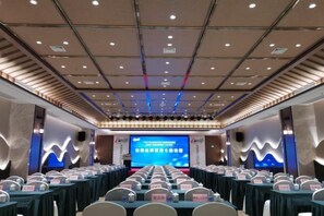 A conference room with a stage, rows of tables, and chairs. - Yongfu County Golden Coast Royal Blessing Hotel (Yongfu)