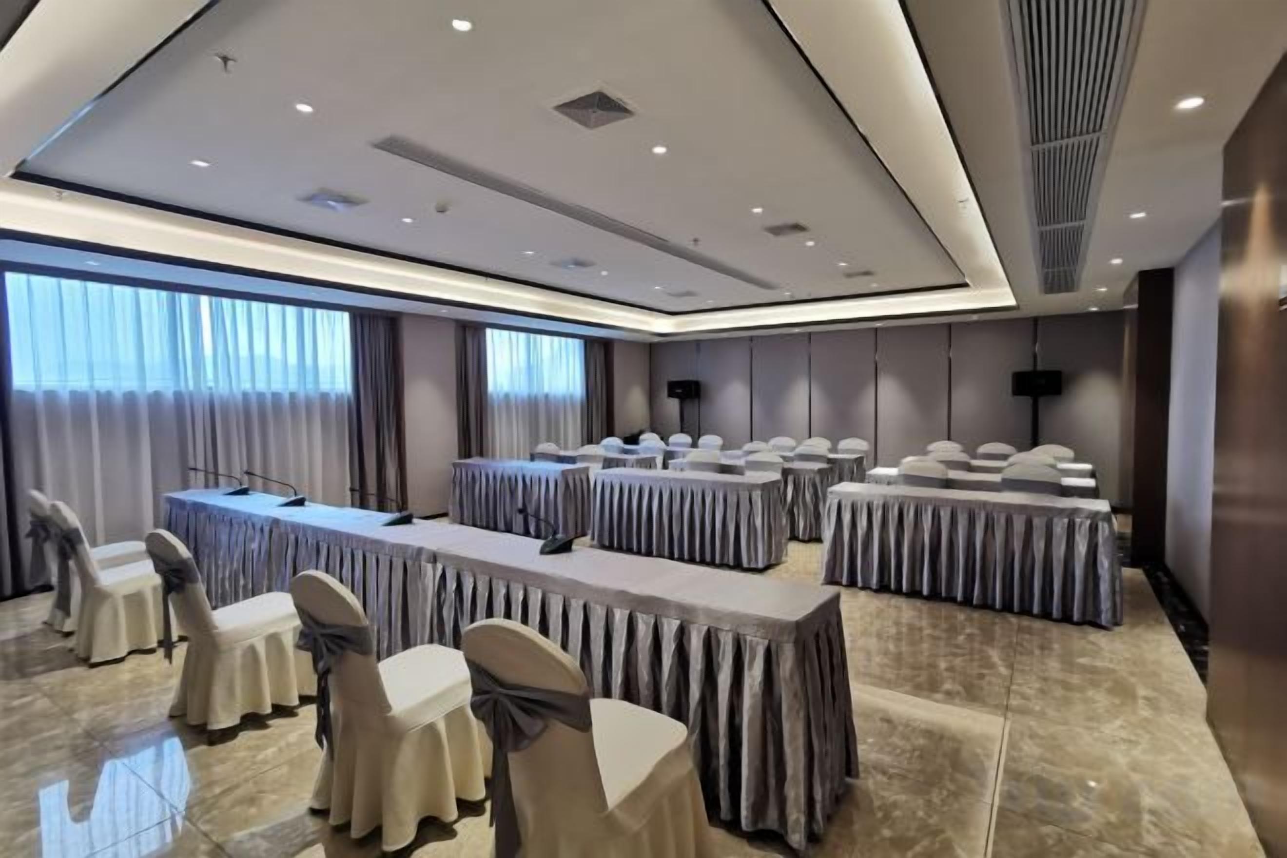 A conference room with multiple tables, chairs, and a large screen.