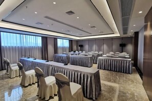 A conference room with multiple tables, chairs, and a large screen. - Yongfu County Golden Coast Royal Blessing Hotel (Yongfu)
