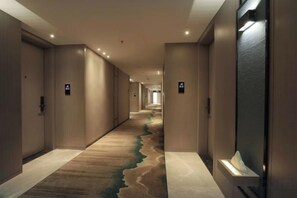 A long corridor with doors on both sides, carpeted floors, and ceiling lights. - Yongfu County Golden Coast Royal Blessing Hotel (Yongfu)