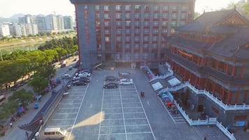 A multi-story hotel with a traditional architectural style, a parking lot, and a river in the background.