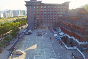 A multi-story hotel with a traditional architectural style, a parking lot, and a river in the background. - Yongfu County Golden Coast Royal Blessing Hotel (Yongfu)