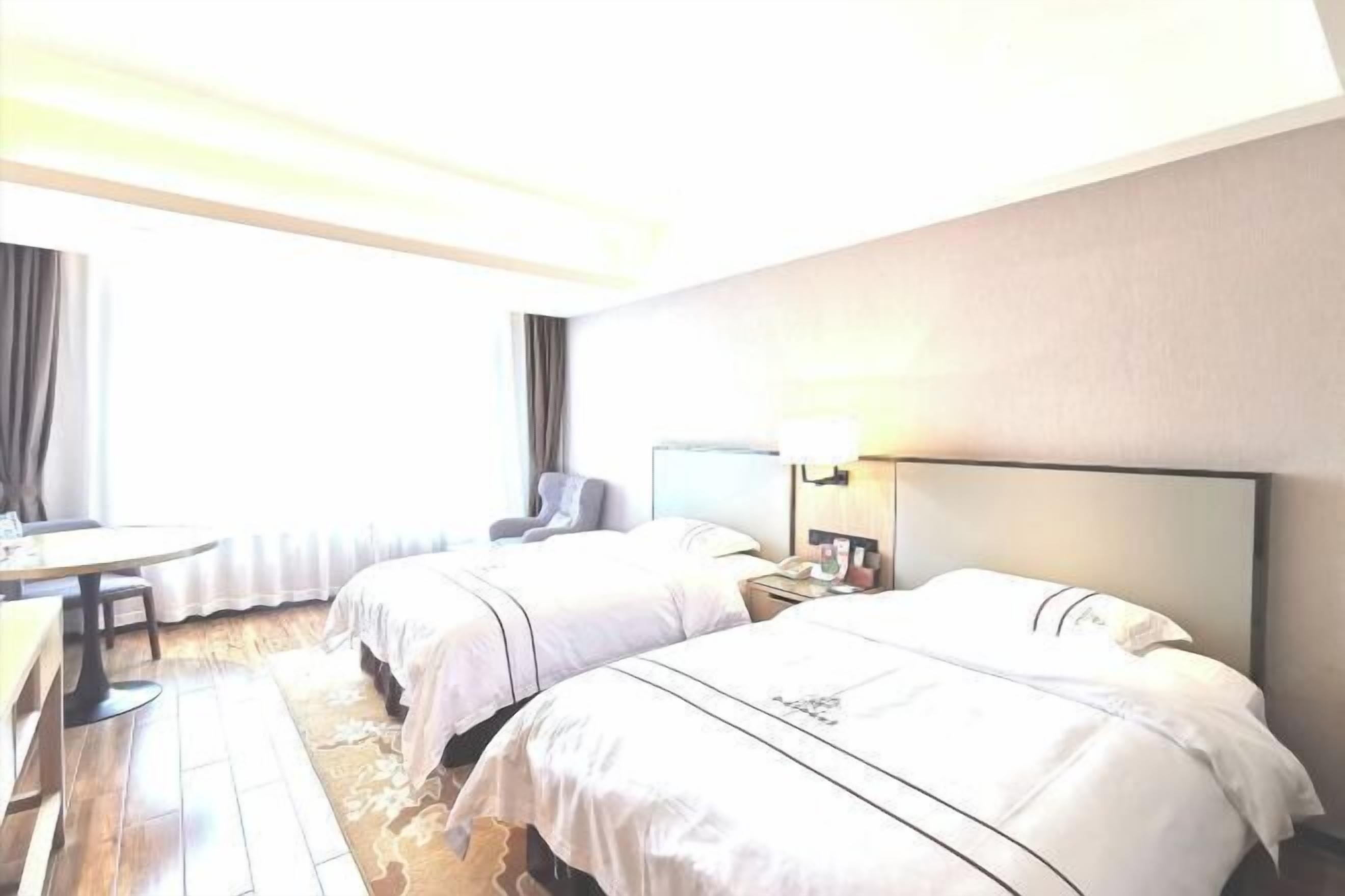 A hotel room with two beds, a desk, and a chair.