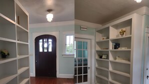 A hallway with wooden flooring, white shelving units, a black door, and a window with a view of greenery outside. - Welcome To Downtown Pickens close to Clemson and Lake Keowee (Pickens)
