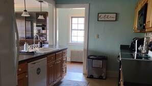 A kitchen with wooden cabinets, a dishwasher, a refrigerator, and a window providing natural light. - Welcome To Downtown Pickens close to Clemson and Lake Keowee (Pickens)