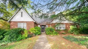 A two-story brick house with a front porch, a central door, and a small front yard with a pathway leading to the entrance. - Welcome To Downtown Pickens close to Clemson and Lake Keowee (Pickens)