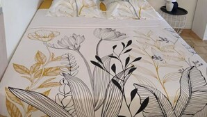 Une chambre à coucher avec une tête de lit bleue, une literie à motifs floraux et une table de chevet avec une lampe.