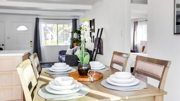 A dining area with a wooden table set for four, surrounded by chairs. A vase with a plant is placed in the center. - Milpitas Central Private 3Bd Home~ Convenience! (Milpitas)