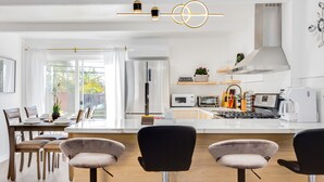 A modern kitchen with a central island, bar stools, and a dining area with a table and chairs. - Milpitas Central Private 3Bd Home~ Convenience! (Milpitas)