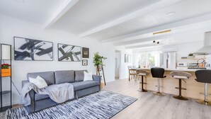A modern living room with a grey sofa, a patterned rug, and a dining area with bar stools. - Milpitas Central Private 3Bd Home~ Convenience! (Milpitas)