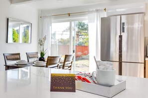 Een moderne keuken met een koelkast, een eettafel met stoelen en een raam met gordijnen.