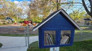 A small blue library kiosk with a sign instructing to clean up after dogs. - Cozy Neutral Farmhouse Welcomes Peaceful Retreat (Muskegon)