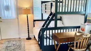 A room with a bunk bed, a desk with a chair, a lamp, and a rug. - Cozy Neutral Farmhouse Welcomes Peaceful Retreat (Muskegon)