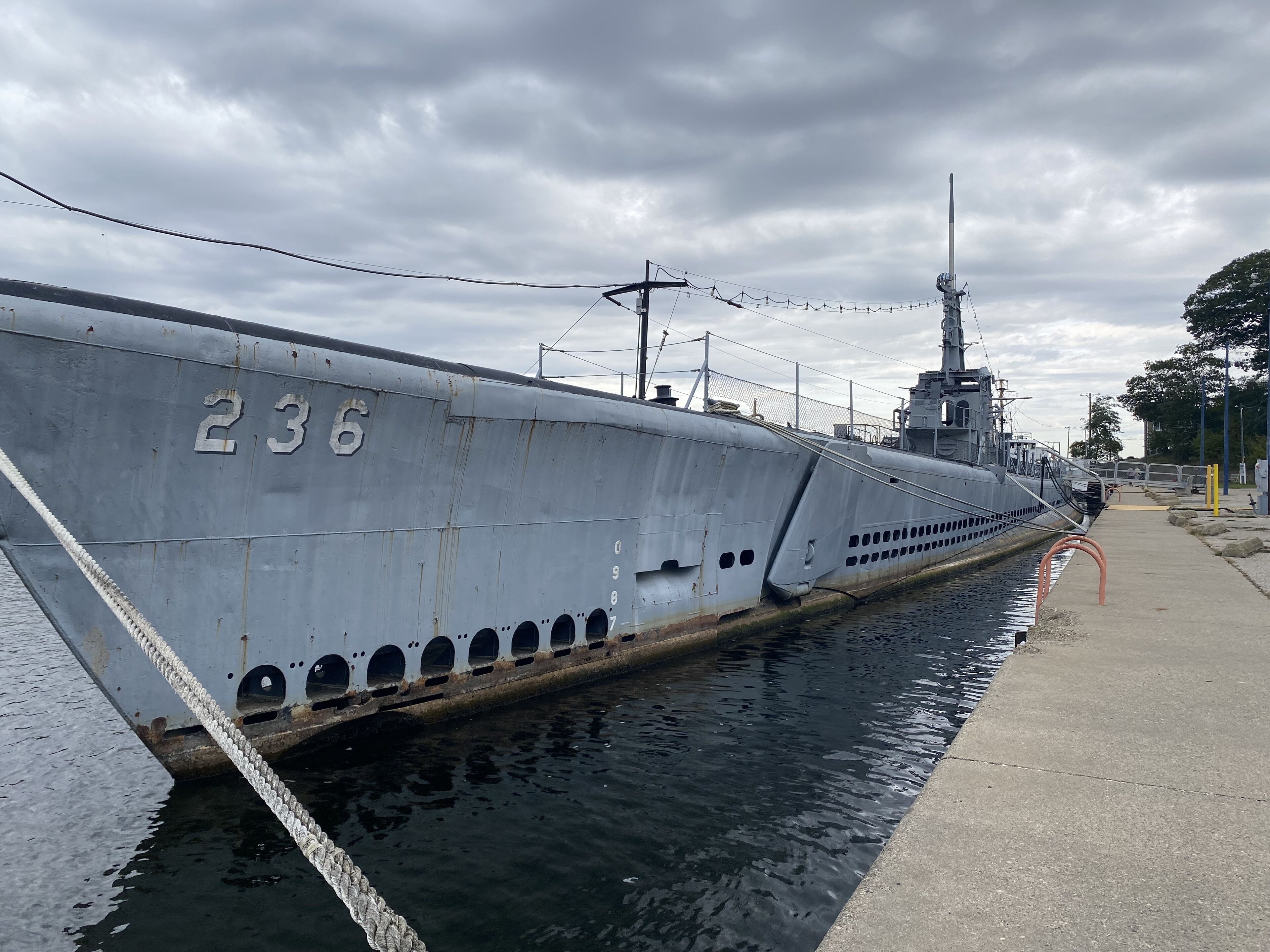 A large, grey submarine docked in a harbor with a visible number "236" on its side.