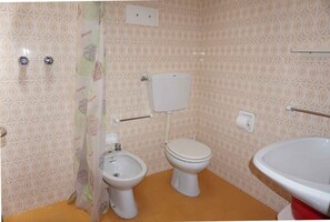 Ein Badezimmer mit gemusterten Fliesen, einer Toilette, einem Bidet und einem Waschbecken.