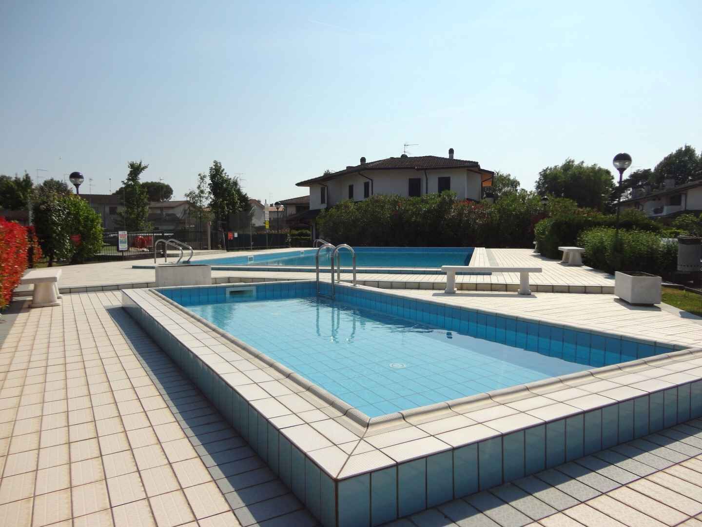 A rectangular pool with two ladders, surrounded by a tiled deck.