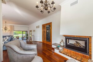 A spacious living room with a fireplace, a leather sofa, and a chandelier.