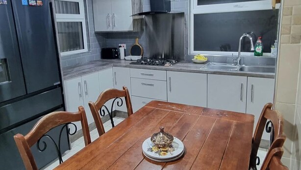 A kitchen with a dining table, chairs, a stove, cabinets, and a window. - House Sleeps 6 with Private Garden (Birmingham)