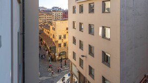 Un carrer estret amb edificis a ambdós costats, una zona per a vianants i una vista del paisatge urbà a la distància.