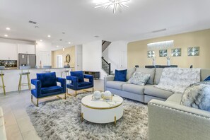 Relax in this stylish living room with a sofa, coffee table, and armchairs, plus a staircase leading to an upper level.