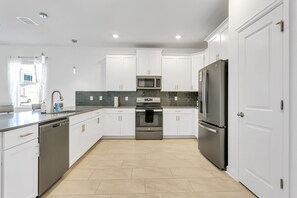 Enjoy cooking in this well-lit kitchen with sleek cabinetry, an oven, and a large refrigerator.