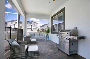 Relax on the patio with wicker furniture and a stainless steel grill, surrounded by a glass railing offering views of the neighborhood.