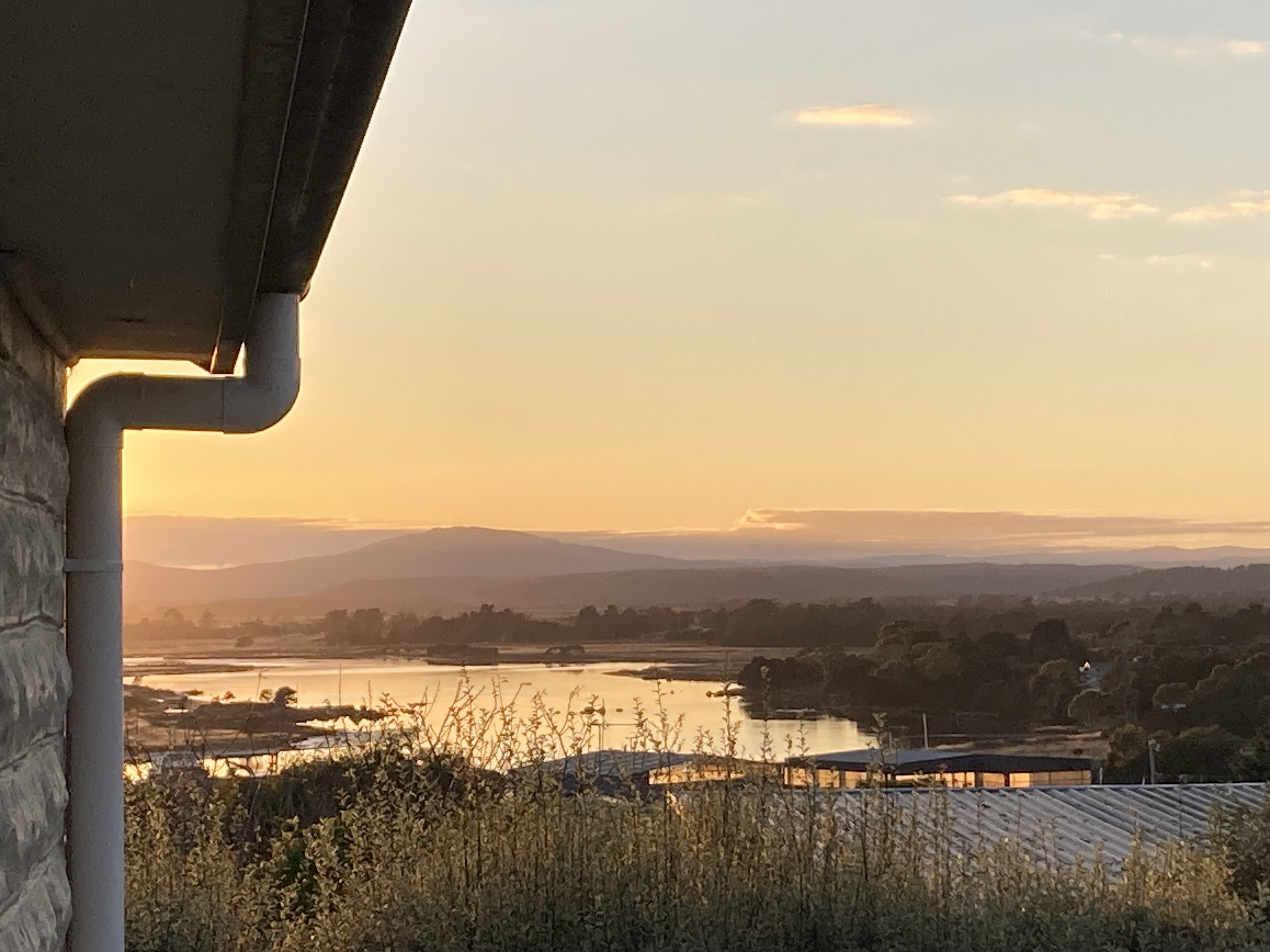 Vista de un río con colinas circundantes y un edificio de techo inclinado.