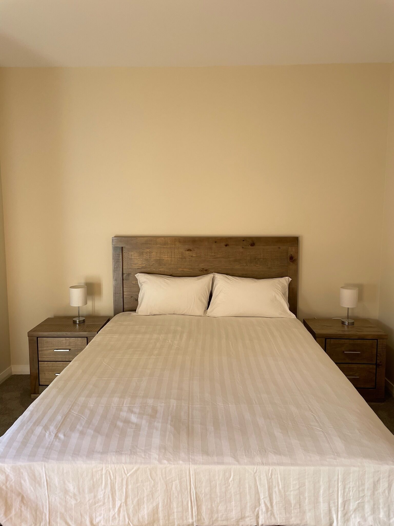 A standard hotel room with a large bed, two bedside tables, and a headboard.