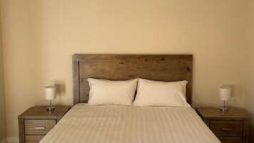 A standard hotel room with a large bed, two bedside tables, and a headboard.