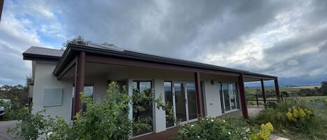 A modern house with a covered porch, large glass doors, and a view of the countryside.