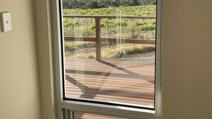 A room with a large sliding glass door leading to an outdoor deck with a vineyard view. - Kesehills Wines Villa (Mount Pleasant)