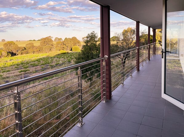 A balcony with a metal railing overlooking a vineyard and open fields. - Kesehills Wines Villa (Mount Pleasant)